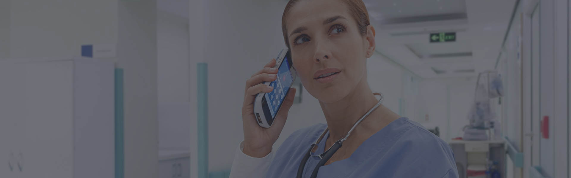 Female medical professional holding connectivity mobile device to ear in a hospital setting